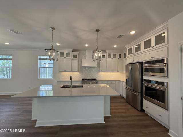 kitchen with wall chimney range hood, appliances with stainless steel finishes, a healthy amount of sunlight, and a sink