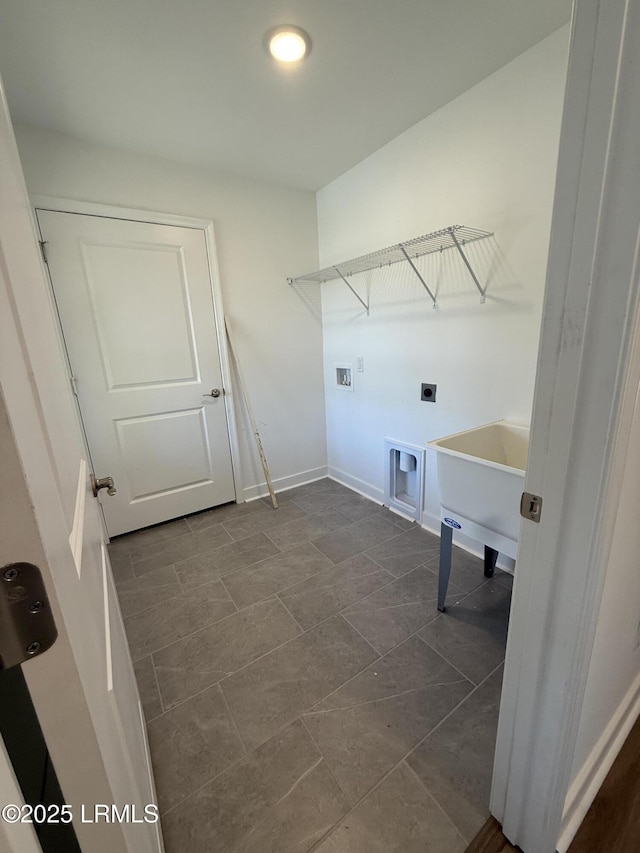 clothes washing area featuring baseboards, a sink, laundry area, and washer hookup