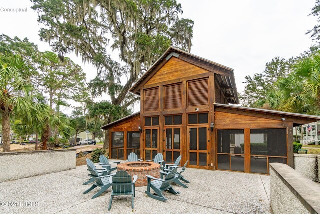 back of house with a sunroom, a patio area, and an outdoor fire pit