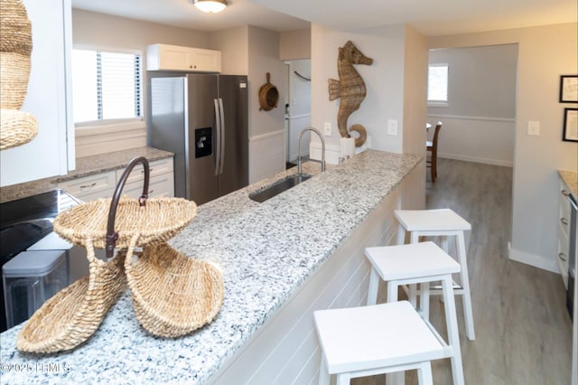 663 William Hilton Pkwy Unit 442, Hilton Head Island, SC 29928 - kitchen with stainless steel fridge with ice dispenser, wood finished floors, light stone counters, and white cabinets