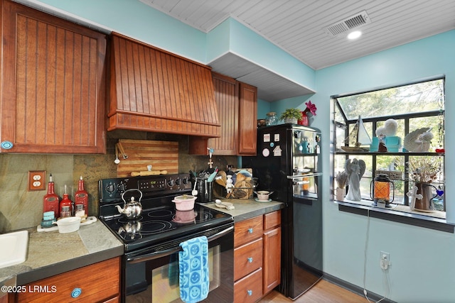 31 Anchorage Pt Unit 31, Hilton Head Island, SC 29928 - kitchen with tasteful backsplash, custom exhaust hood, visible vents, brown cabinetry, and black appliances
