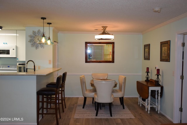 dining room featuring hardwood / wood-style floors, ornamental molding, and a textured ceiling