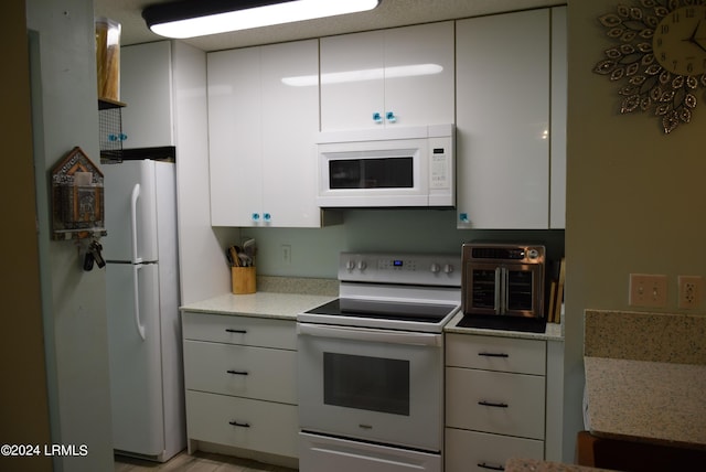 kitchen with white appliances, light stone countertops, and white cabinets