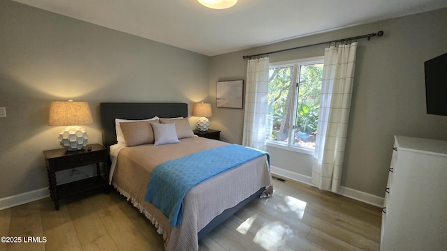 bedroom featuring multiple windows, baseboards, and wood finished floors