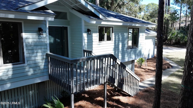 property entrance with a shingled roof and a wooden deck