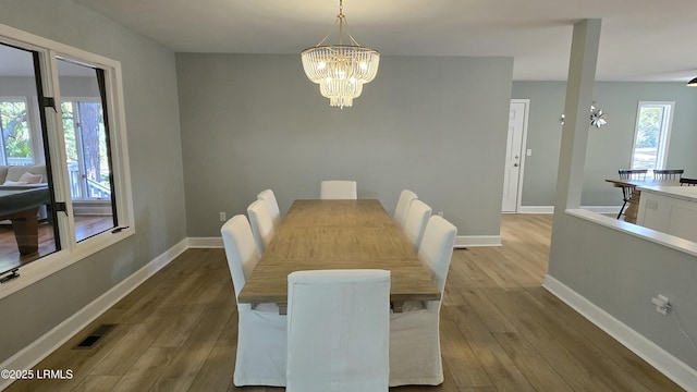 dining area with a notable chandelier, baseboards, visible vents, and wood finished floors