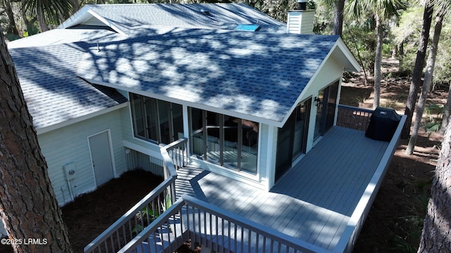 view of side of property with a shingled roof, a sunroom, stairway, a wooden deck, and a chimney