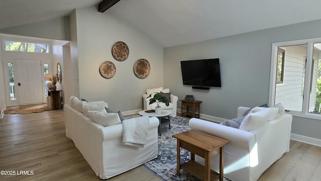 living area with high vaulted ceiling, baseboards, beamed ceiling, and light wood finished floors
