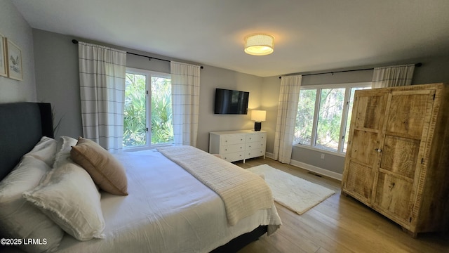 bedroom with light wood-type flooring, visible vents, and baseboards