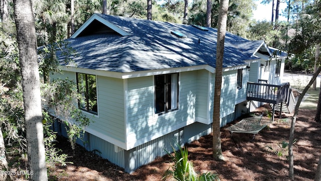 view of side of home with stairway and roof with shingles