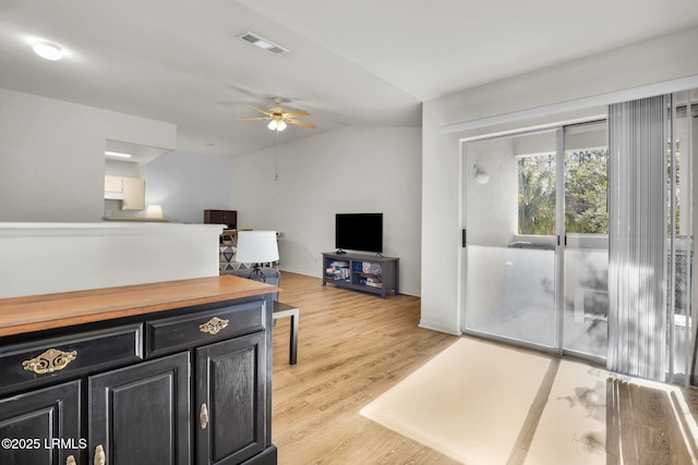 living room with a ceiling fan, baseboards, vaulted ceiling, visible vents, and light wood-style floors