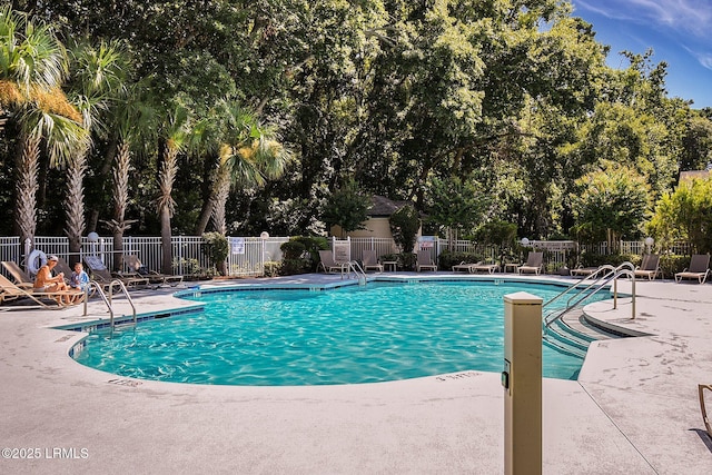 community pool with a patio area and fence