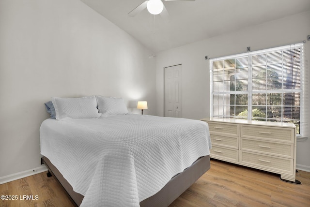 bedroom with a ceiling fan, vaulted ceiling, light wood-style flooring, and baseboards