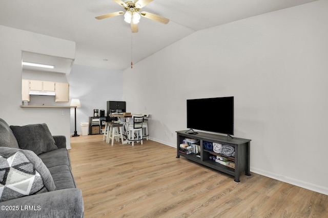 living area with light wood-style floors, vaulted ceiling, baseboards, and ceiling fan