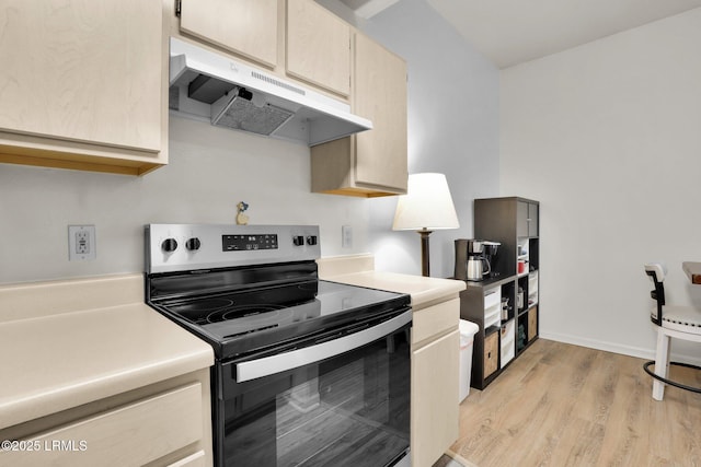 kitchen featuring light wood-type flooring, light countertops, stainless steel electric range oven, and under cabinet range hood