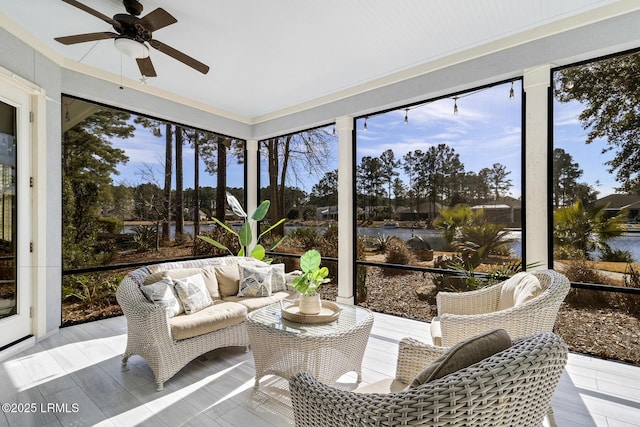 sunroom with ceiling fan and a water view