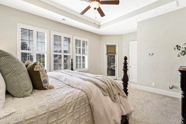 bedroom with ceiling fan, light colored carpet, and a tray ceiling