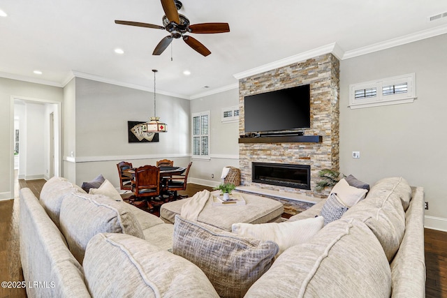 living room featuring dark wood-type flooring, ceiling fan, ornamental molding, and a fireplace