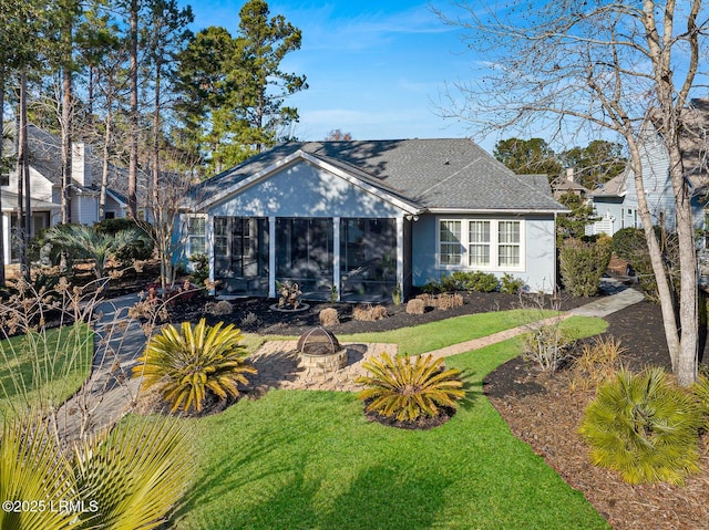 view of front of house featuring a sunroom, a fire pit, and a front yard