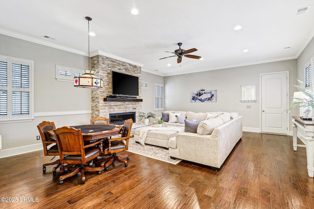 living room featuring crown molding, a stone fireplace, and dark wood-type flooring