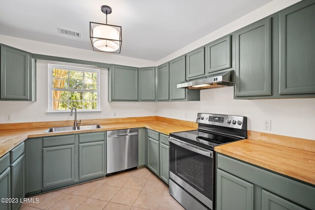 7 Grandiflora Ln, Beaufort, SC 29907 - kitchen with stainless steel appliances, under cabinet range hood, a sink, light tile patterned floors, and green cabinets