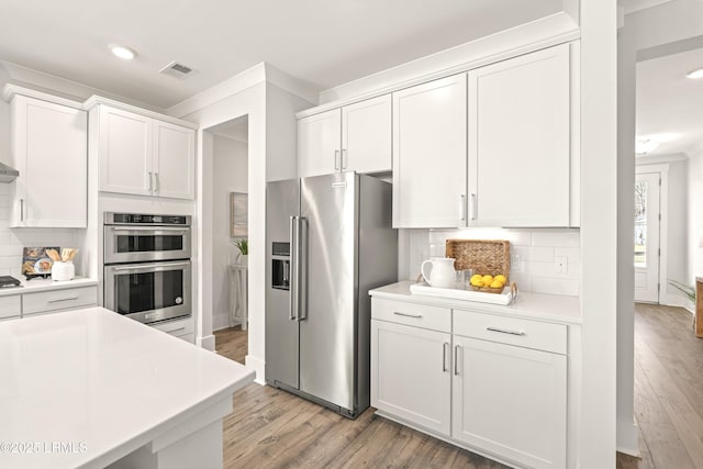 kitchen featuring stainless steel appliances, light countertops, visible vents, and white cabinetry