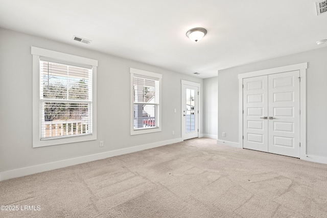 carpeted spare room featuring baseboards and visible vents