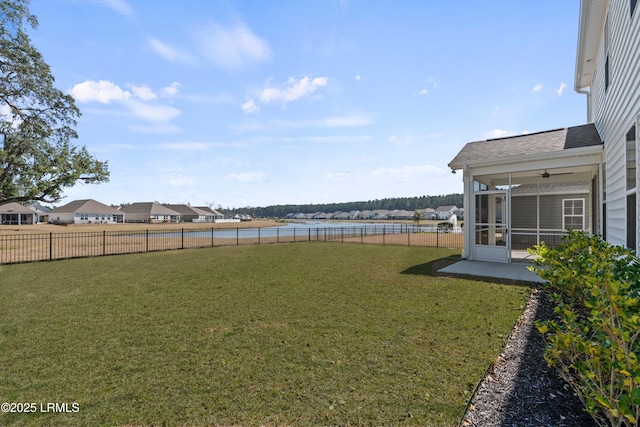 view of yard featuring a water view, a sunroom, and a fenced backyard