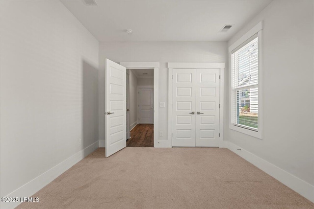 unfurnished bedroom featuring carpet floors, a closet, visible vents, and baseboards