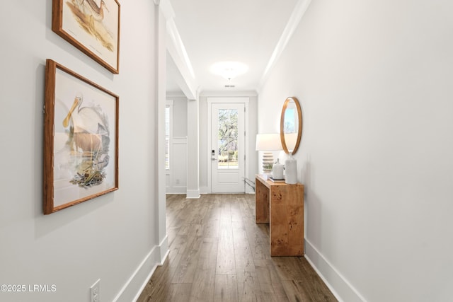 corridor with hardwood / wood-style floors, baseboards, and crown molding