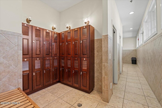 hallway with a wainscoted wall, tile walls, and light tile patterned flooring