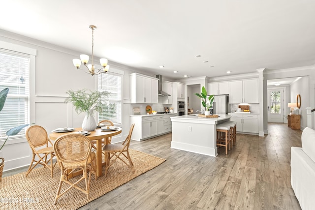 dining space with light wood-type flooring, a notable chandelier, crown molding, and recessed lighting