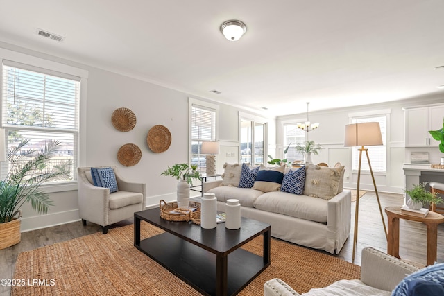 living area with light wood-style flooring, visible vents, and a chandelier