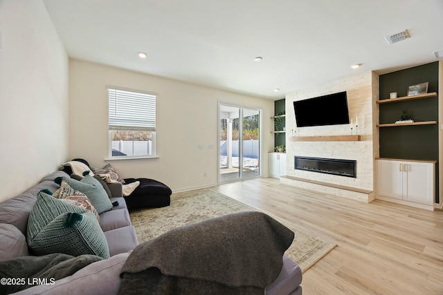 living room featuring plenty of natural light, a fireplace, and light hardwood / wood-style flooring