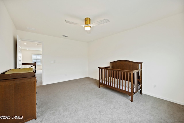 bedroom featuring a nursery area, ceiling fan, and carpet flooring