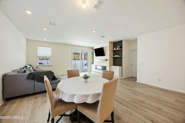 dining space with a stone fireplace and light wood-type flooring