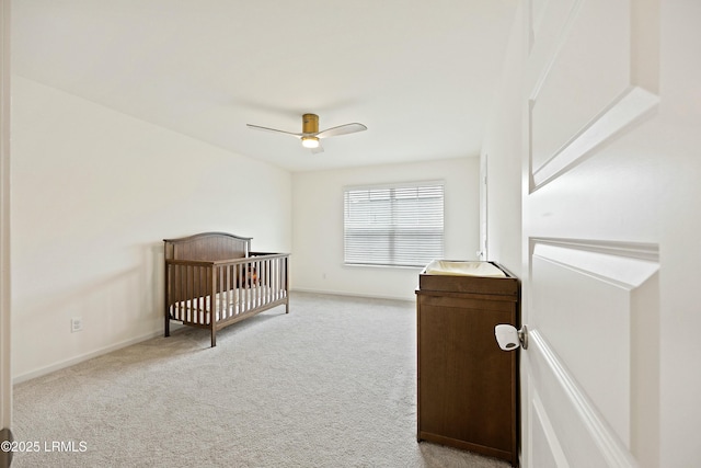 carpeted bedroom featuring a nursery area and ceiling fan