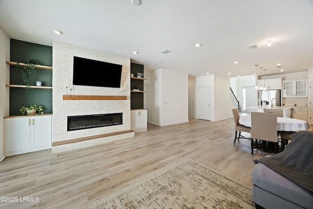 living room with a fireplace and light wood-type flooring