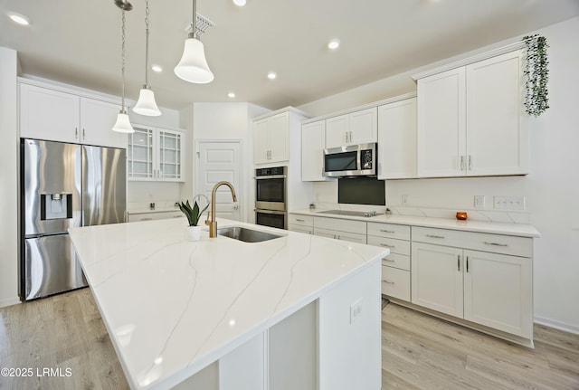 kitchen featuring stainless steel appliances, an island with sink, and white cabinetry