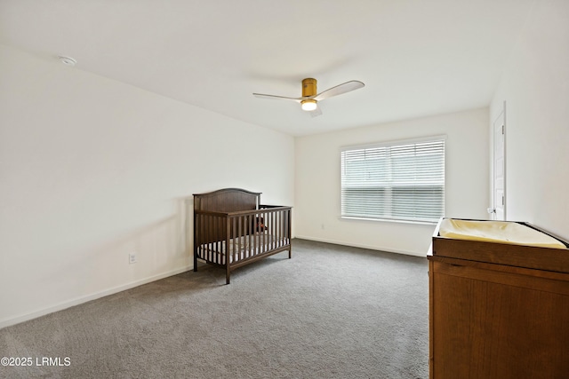 carpeted bedroom with a crib and ceiling fan