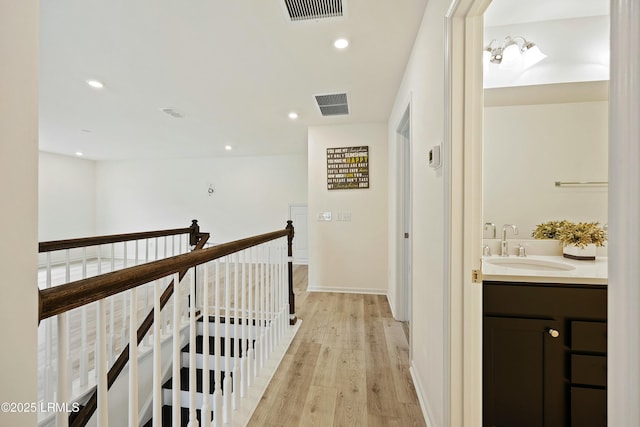 hallway with sink and light hardwood / wood-style flooring