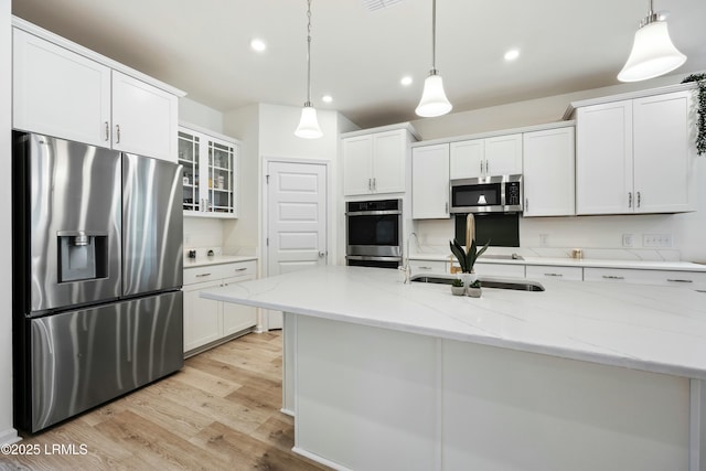 kitchen with light stone counters, stainless steel appliances, decorative light fixtures, and white cabinets