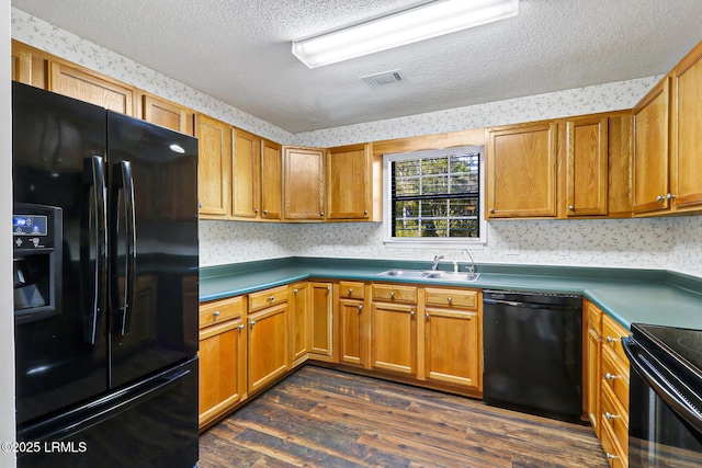 kitchen with wallpapered walls, black appliances, dark wood-type flooring, visible vents, and a sink