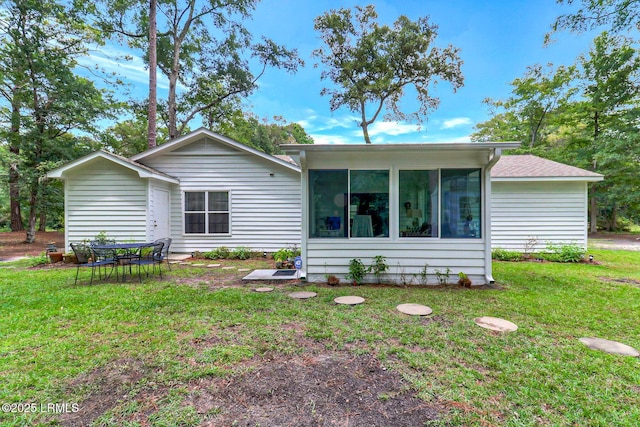 rear view of property featuring a sunroom and a lawn