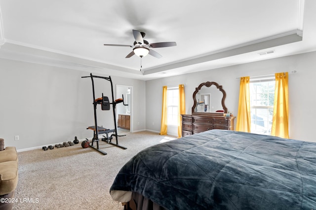 carpeted bedroom featuring a raised ceiling, ornamental molding, connected bathroom, and ceiling fan