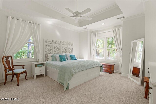 bedroom featuring multiple windows, a tray ceiling, light colored carpet, and ceiling fan