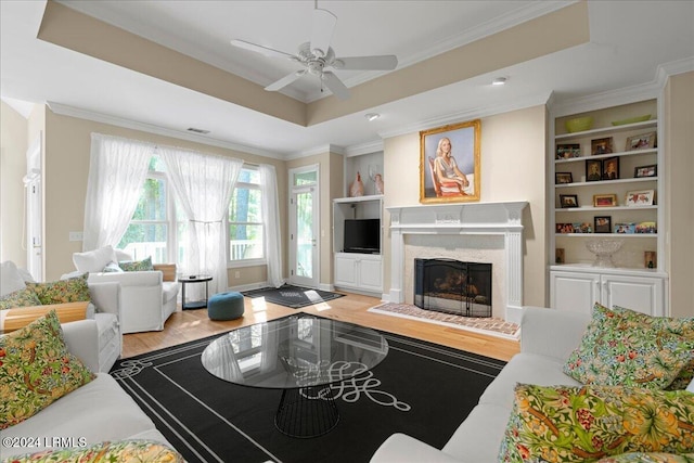 living room with crown molding, a premium fireplace, and a tray ceiling