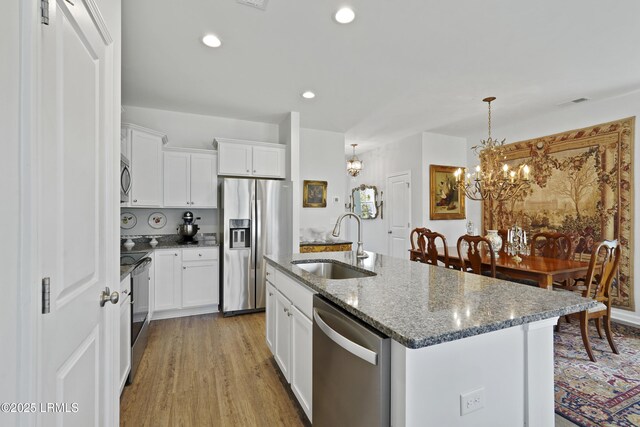 257 Garden Gate Cir E, Hardeeville, SC 29927 - kitchen with appliances with stainless steel finishes, a chandelier, dark stone countertops, light wood-type flooring, and white cabinetry