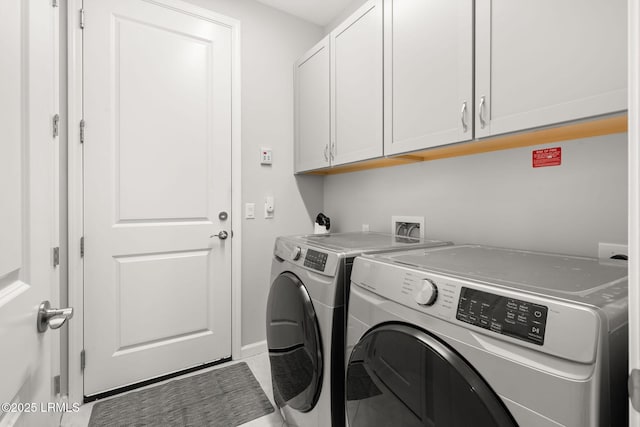 washroom with washer and clothes dryer, cabinet space, and baseboards