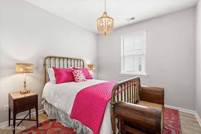 bedroom featuring visible vents, wood finished floors, a chandelier, and baseboards